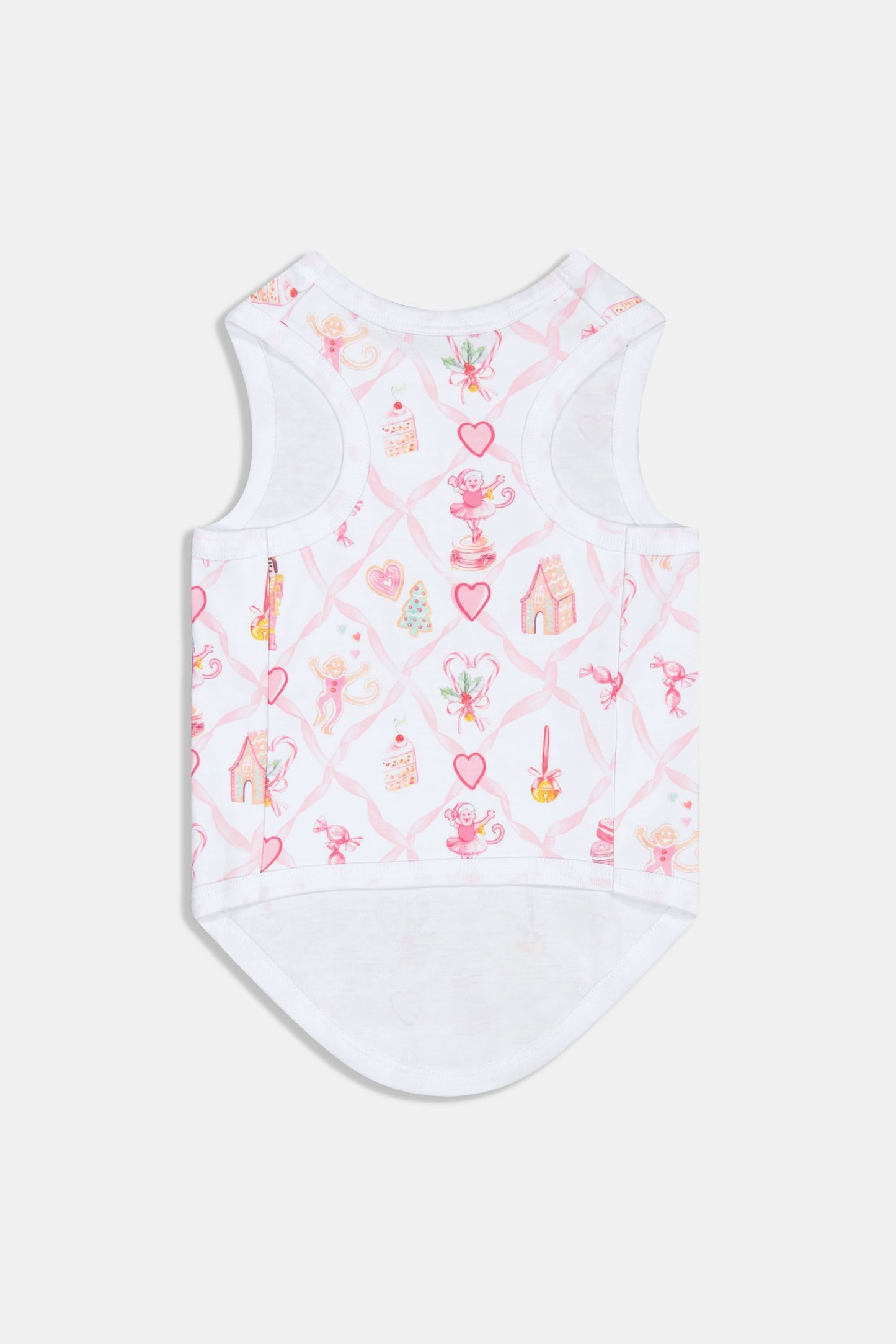 A small, fluffy black dog wears Roller Rabbit Sugarplum Lattice Dog Pajamas with pink and colorful patterns while sitting on a white background and looking slightly to the side.