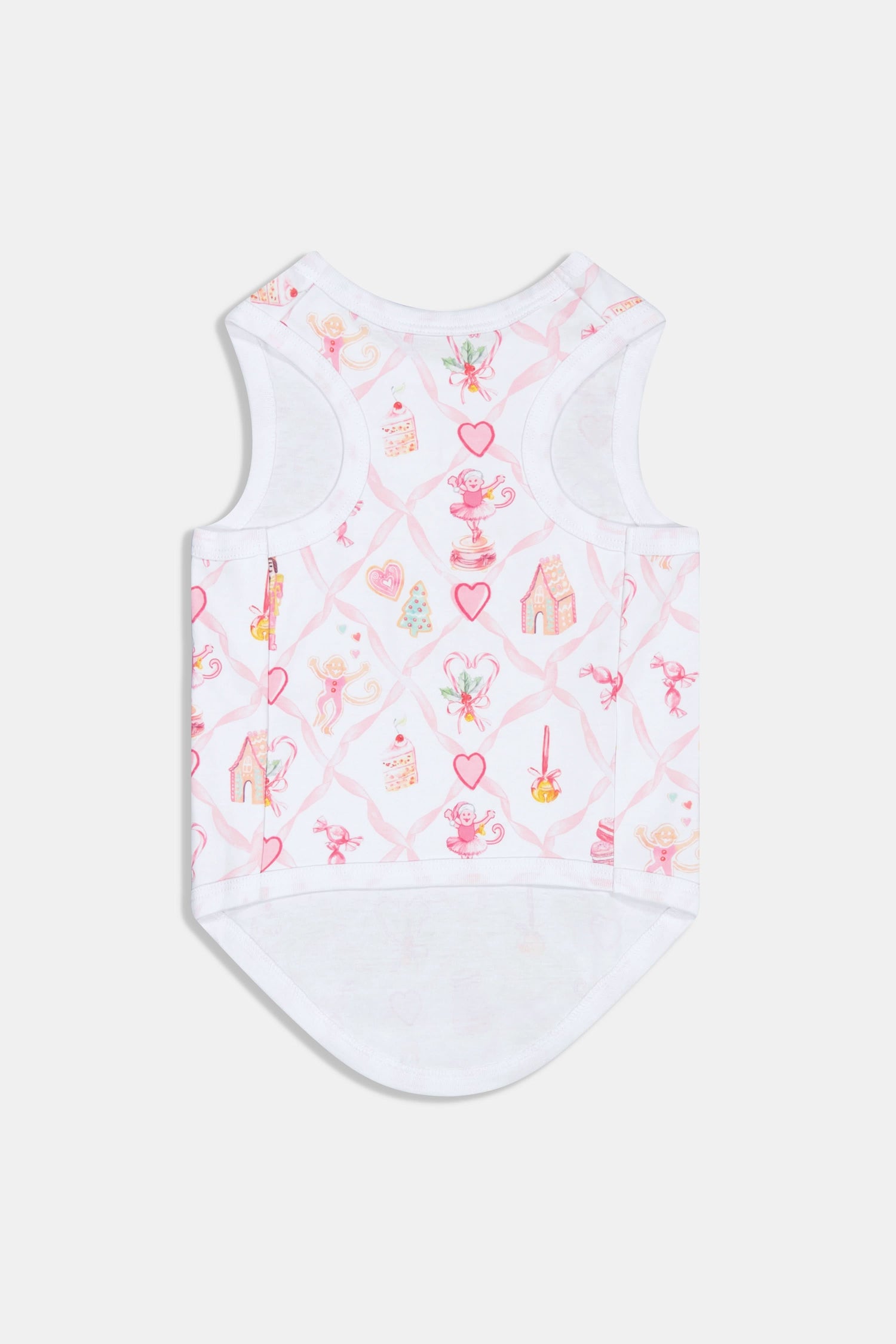 A small, fluffy black dog wears Roller Rabbit Sugarplum Lattice Dog Pajamas with pink and colorful patterns while sitting on a white background and looking slightly to the side.