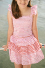 A child wears the Roller Rabbit Kids Starry Dot Sami Skirt in pink and red with star and polka dot patterns, paired with a pink smocked top, standing against a plain light background.