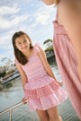 A young girl wears the Roller Rabbit Kids Starry Dot Tory Top in pastel pink with flutter sleeves, paired with a matching skirt featuring red stars and white polka dots. Only her torso and part of her face are visible.