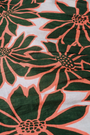 A close-up of the fabric used in the Blooming Daisies Shiv Caftan by Roller Rabbit, featuring bold dark green flowers outlined in orange on a white background—ideal for a vibrant floral statement.