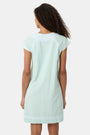 A woman with long curly hair wears the Roller Rabbit Faith Dress, a seaglass-green short-sleeved dress with hand embroidery and a notched neckline, standing against a plain light background.