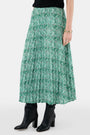 Someone wears the Roller Rabbit Fern Floral Megan Skirt—a green and white pleated maxi—paired with a black top, gold bracelets, and black heeled boots, shown from the waist down against a plain background.