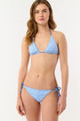 A person wears the Roller Rabbit Fish Stripe/Ruban Serena Bikini Bottom in blue with side ties, shown from torso to upper thighs against a plain white background. This bikini bottom offers UPF 50+ sun protection.