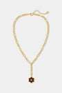 The Raya Floral Necklace by Roller Rabbit features a burgundy floral pendant with a green center on a gold chain, displayed against a white background.