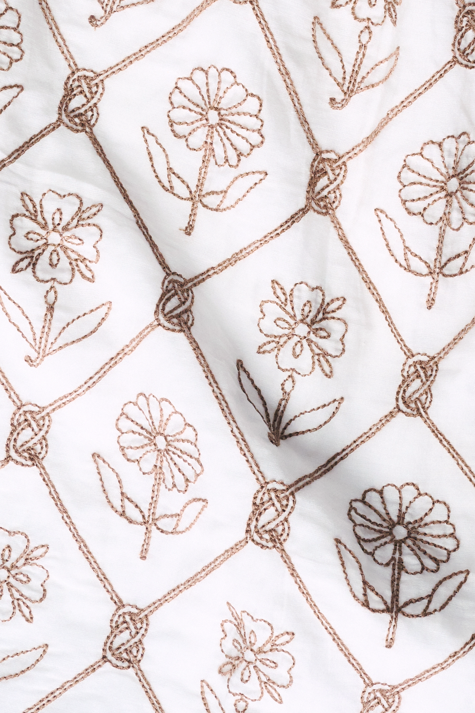 A woman with blonde hair wears the Infinity Floral Embroidery Stevie Top by Roller Rabbit, featuring vintage floral embroidery and a drawstring neckline, standing against a plain white background and smiling softly.
