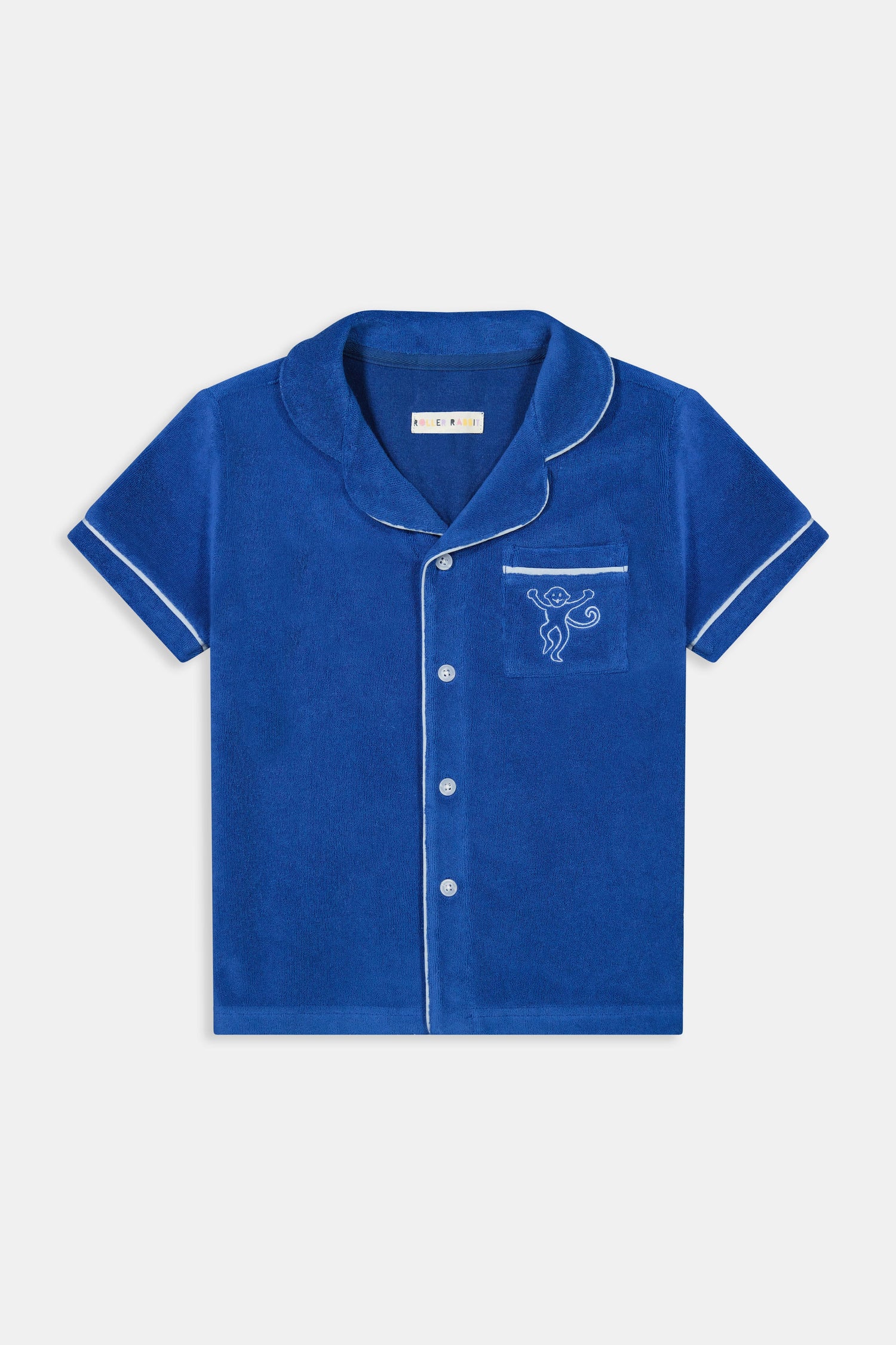 A young child wearing the Roller Rabbit Kids Monkey Embroidery Leo Polo—a navy top with white trim and an embroidered monkey on the chest pocket—smiles with arms raised overhead.