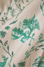 A person wears the Roller Rabbit Woodland Toile Quilted Azure Mini Skirt, featuring green floral patterns, green trim, a side slit, and paired with a matching white jacket—an ideal fall fashion ensemble.
