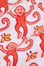 Close-up of Monkey Polo Pajamas: playful red monkey pattern with smiling faces and curled tails, plus yellow and orange leaves on a light pink background—perfect for matching pajama sets in soft pima cotton.