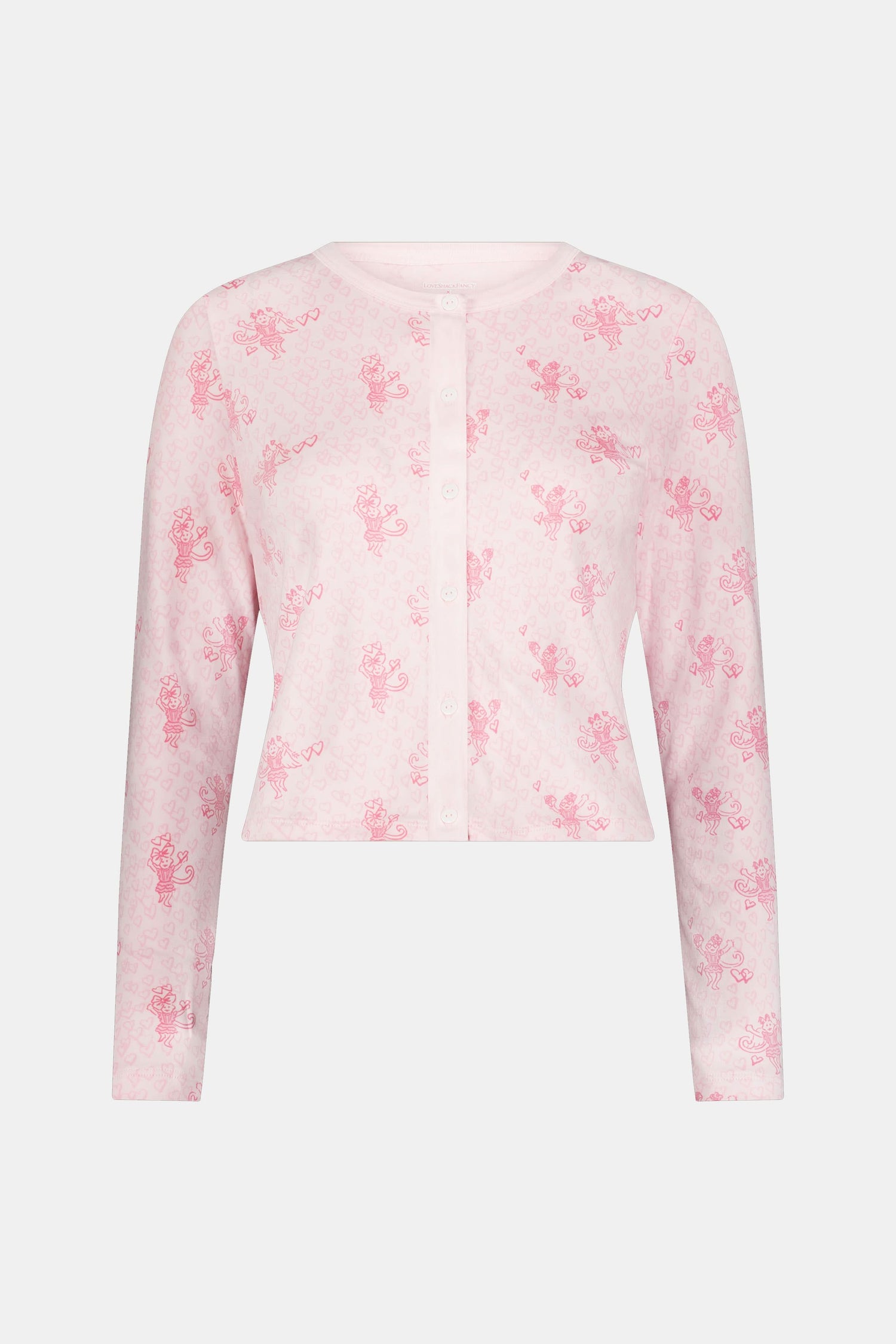 Wearing the Cupid's Kiss Nessa Cardigan by Roller Rabbit, a woman stands against a plain light background. The soft cardigan features a charming pink and white design with a delicate floral pattern, perfectly complemented by her matching sleep mask.