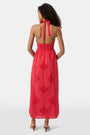 A woman with long curly hair wears the Roller Rabbit Monaco Geo Penelope Dress, a sleeveless, halter-neck, ankle-length red dress with subtle embroidery. She stands forward in open-toed, low-heeled sandals against a plain white background.