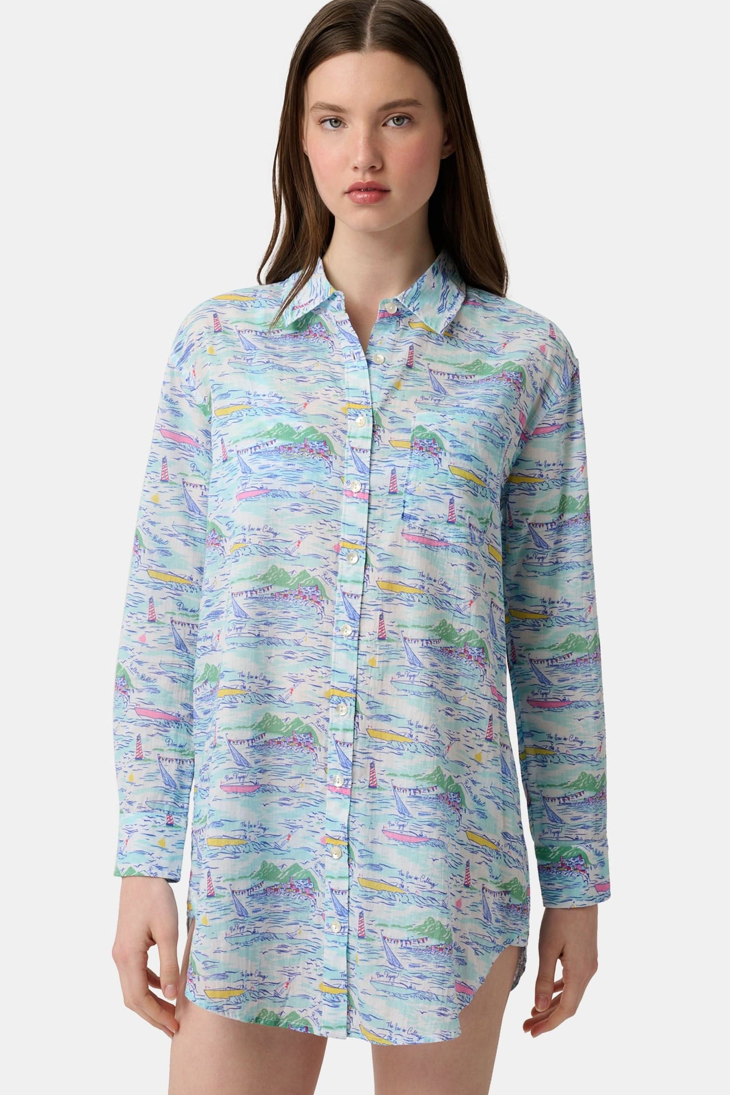 A woman wears the Roller Rabbit Regatta Boyfriend Dress, a loose-fitting cotton voile piece with long sleeves and colorful pastel abstract patterns. The thigh-length dress features a relaxed fit as she stands against a plain, light background.