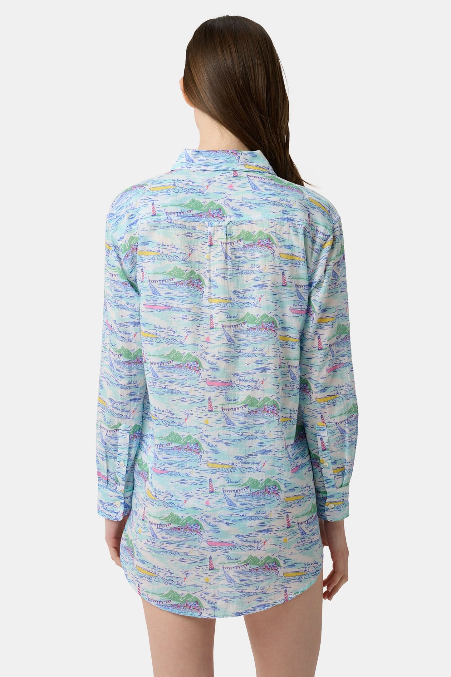 A woman wears the Roller Rabbit Regatta Boyfriend Dress, a loose-fitting cotton voile piece with long sleeves and colorful pastel abstract patterns. The thigh-length dress features a relaxed fit as she stands against a plain, light background.