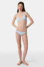 A person wears the Roller Rabbit Regatta Marais Bikini Bottom, featuring a colorful nautical print with boats and lighthouses. The UPF 50+ swimwear offers sun protection. Image is cropped from chest to upper thighs.