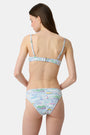 A person wears the Roller Rabbit Regatta Marais Bikini Bottom, featuring a colorful nautical print with boats and lighthouses. The UPF 50+ swimwear offers sun protection. Image is cropped from chest to upper thighs.