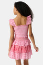 A young girl wears the Roller Rabbit Kids Starry Dot Tory Top in pastel pink with flutter sleeves, paired with a matching skirt featuring red stars and white polka dots. Only her torso and part of her face are visible.