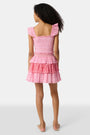 A child wears the Roller Rabbit Kids Starry Dot Sami Skirt in pink and red with star and polka dot patterns, paired with a pink smocked top, standing against a plain light background.
