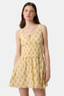 A young woman models the Roller Rabbit Rosa Ditsy Floral Penny Dress, a light yellow sundress with a floral pattern, gathered bodice, and gently flared skirt, set against a plain white background.