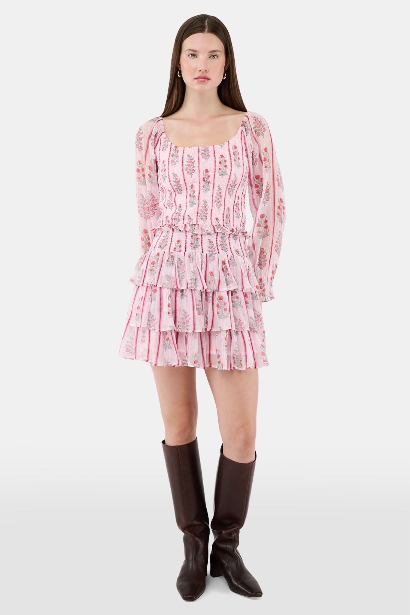 A woman with long brown hair models the Roller Rabbit Rose Ribbon Morgana Top—a pink, floral long-sleeve blouse—against a plain light background.