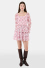A woman with long brown hair models the Roller Rabbit Rose Ribbon Morgana Top—a pink, floral long-sleeve blouse—against a plain light background.