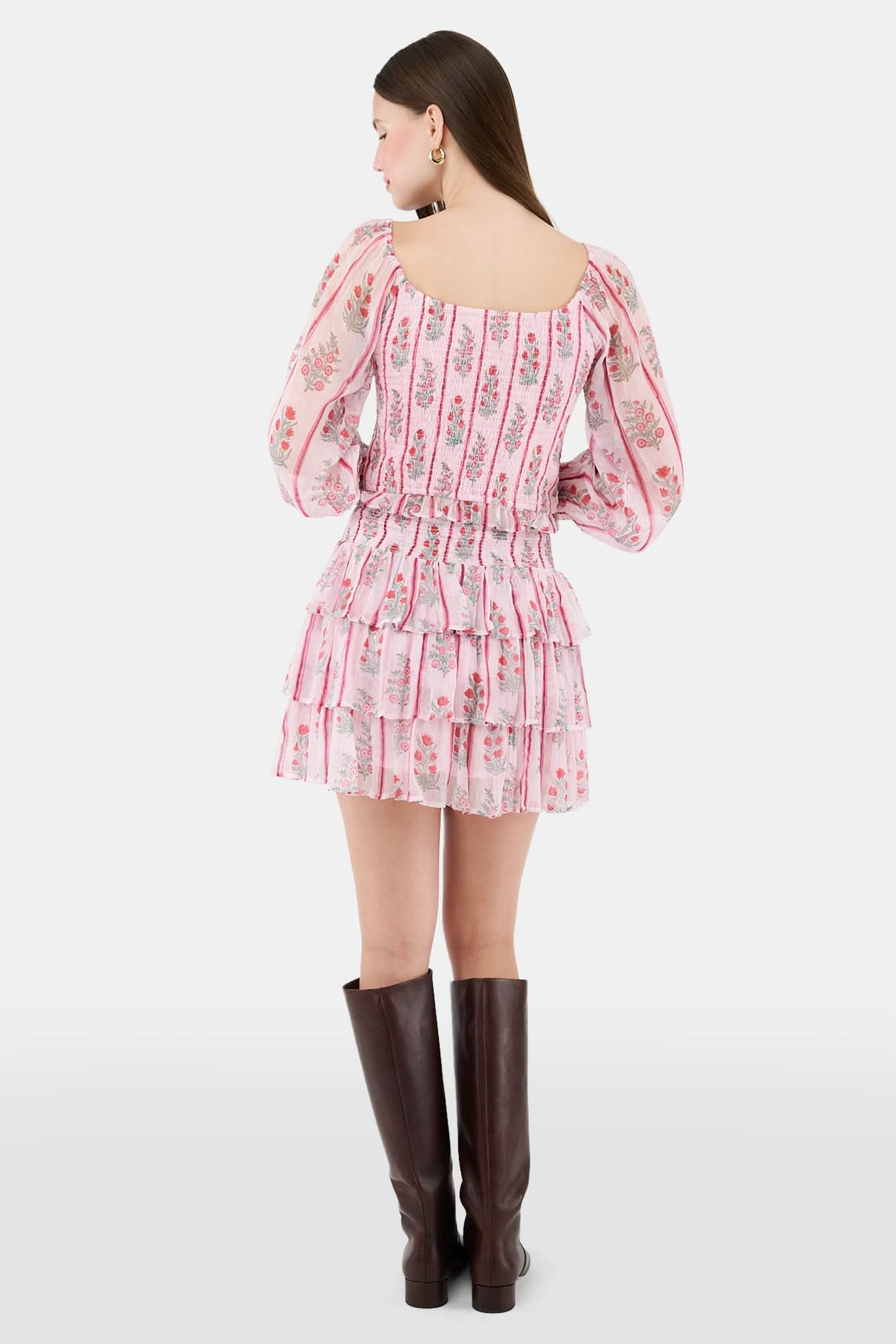 A woman with long brown hair models the Roller Rabbit Rose Ribbon Morgana Top—a pink, floral long-sleeve blouse—against a plain light background.