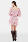 A woman with long brown hair models the Roller Rabbit Rose Ribbon Morgana Top—a pink, floral long-sleeve blouse—against a plain light background.
