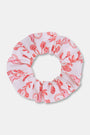 The Rosa Ditsy Monkey Scrunchie by Roller Rabbit features a pink fabric with a red floral print, shown against a white background. This soft scrunchie is gentle on hair.