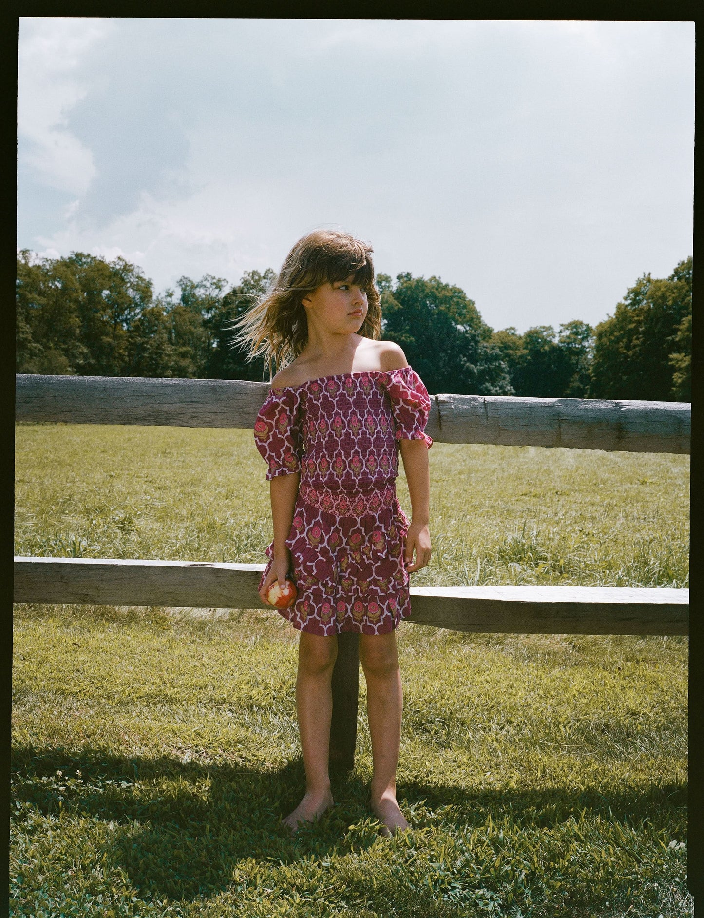 A young child wears the Roller Rabbit Kids Marquis Floral Bibi Skirt paired with maroon heart-accented shoes, standing against a plain white background.