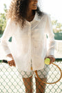 A woman in a straw hat and white scalloped shorts wears the Roller Rabbit Sunny Days Eyelet Girlfriend Shirt, standing against a plain light background.