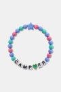 The Roller Rabbit Camp RR Besties Bracelet features pink, blue, and green beads, a blue star bead, white letter beads spelling CAMP R R with a gold-edged green heart as the 