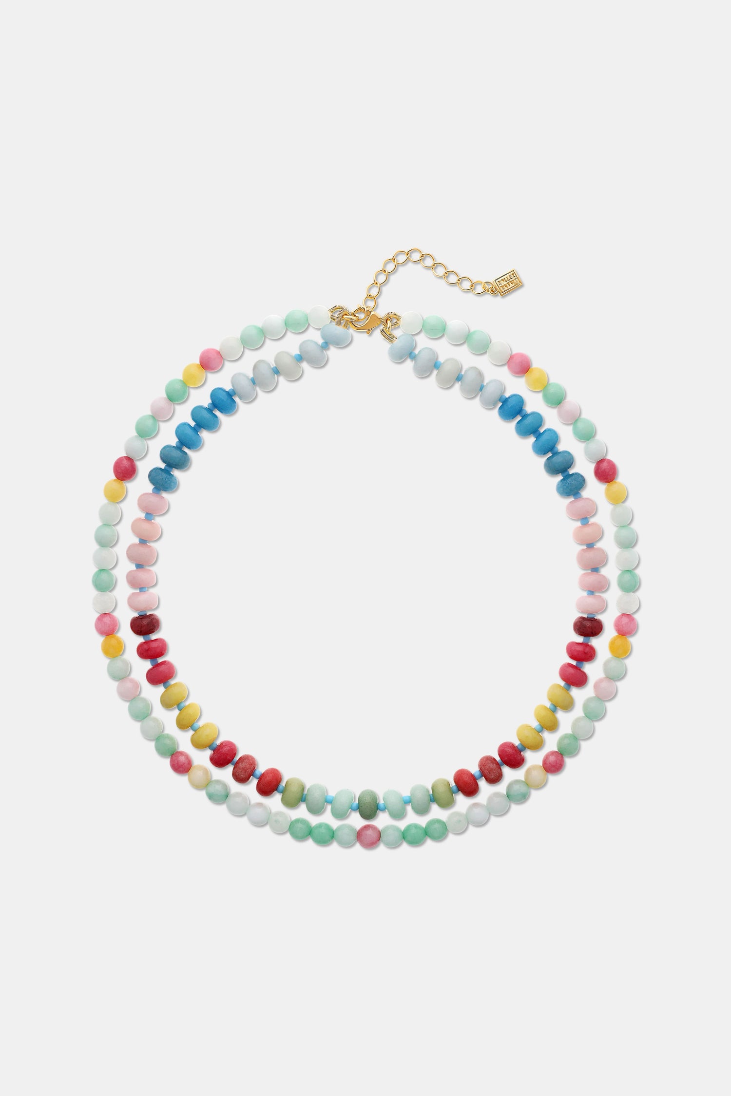 A woman is shown from the shoulders up wearing a cream knit top and the Roller Rabbit Beaded Necklace Stack, featuring colorful beaded chains and a small white flower-shaped bead.