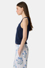 A woman wears the Roller Rabbit Pointelle Sasha Sweater Tank in navy with a textured open-weave design, paired with white shorts featuring blue floral prints. She is shown from shoulders to waist, looking slightly to the side.