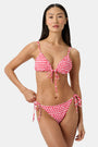 A woman wears the Roller Rabbit Starry Dot Isa Bikini Top, a red triangle bikini with white polka dots and a front tie, shown from shoulders to waist against a plain background.