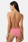 A woman wears the Roller Rabbit Starry Dot Isa Bikini Top, a red triangle bikini with white polka dots and a front tie, shown from shoulders to waist against a plain background.