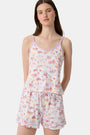 A woman wears the Roller Rabbit Summer Memories Mischa Set, a 100 Pima cotton cami tank and boxer set with a pastel travel icon print on white, standing against a light background.