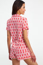 A person stands with their back to the camera, wearing Monkey Polo Pajamas—a red and white patterned short-sleeve pima cotton set—against a plain white background.