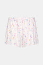 Wearing Roller Rabbit's Candy Heart Stripe Jones Shortie pajama shorts, featuring a pastel hearts, bows, and stars pattern, this person stands against a light background.