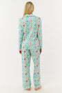 A woman stands barefoot against a white background, wearing Roller Rabbit Ornament Trellis Long Sleeve Polo Pajamas—holiday PJs with a blue, green, and pink geometric diamond print, made from 100 Pima cotton.